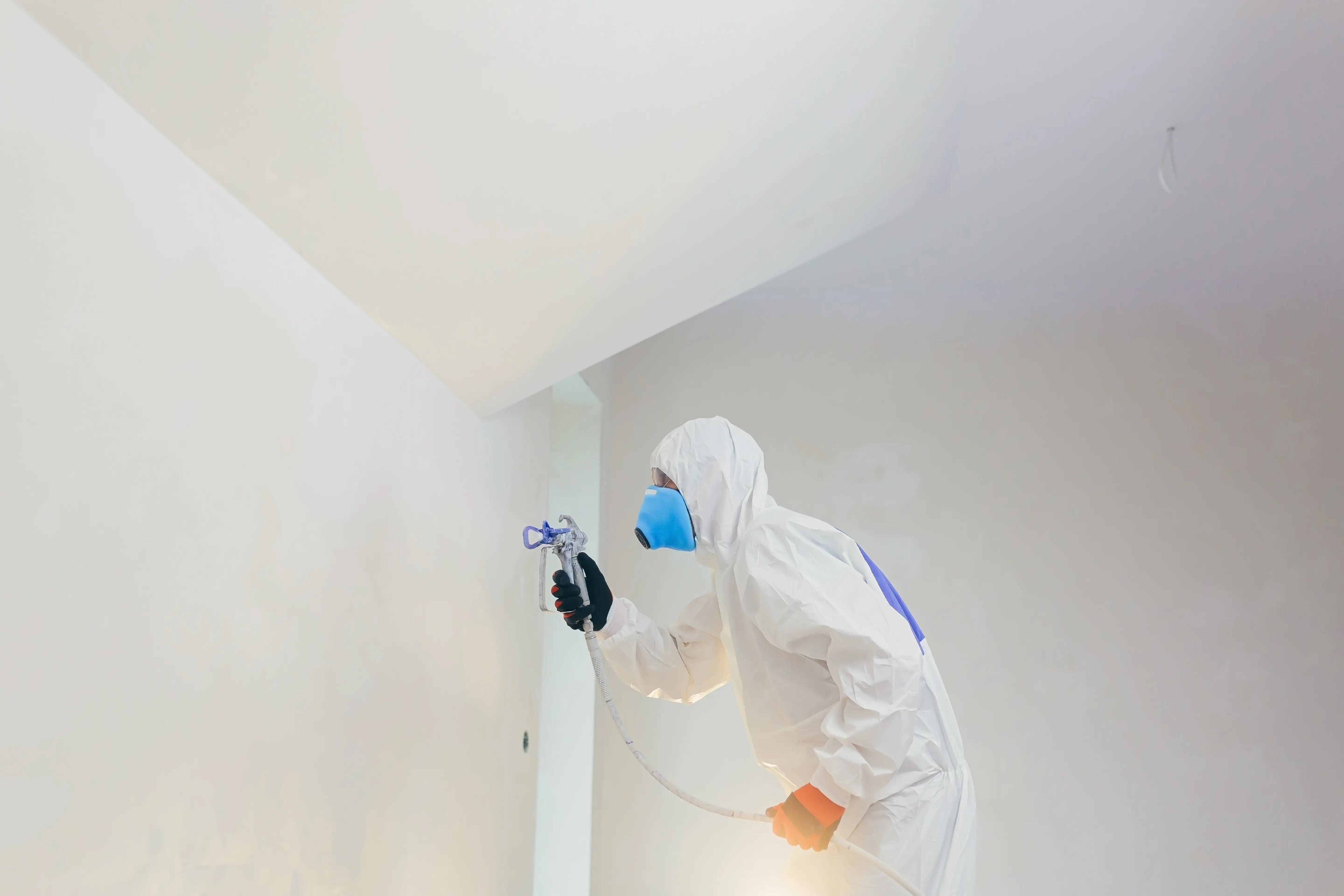 worker paints wall with airless paint sprayer - CES HIRE-1
